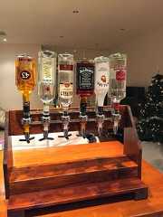 a wooden table topped with glasses filled with alcohol next to a christmas tree in a living room