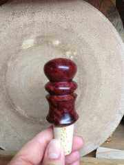 a hand is holding a wooden object in front of a plate