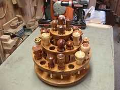 a wooden stand with many vases on it in a room filled with woodworking tools