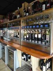 several wine bottles are lined up on the shelves in a bar with glass doors and wooden counter tops