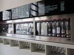 a row of wine glasses sitting on top of a metal shelf filled with bottles and glasses