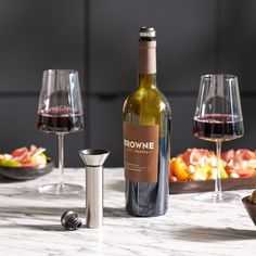 a bottle of wine sitting on top of a table next to two glasses of wine