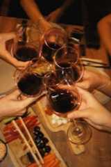 several people holding wine glasses over a table with food and chopsticks on it