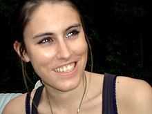 a young woman smiling for the camera with trees in the background