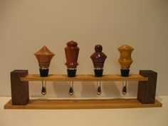 five vases are lined up on a wooden shelf in front of a white wall