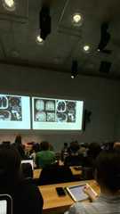 people are sitting at tables in front of a projector screen with pictures on it