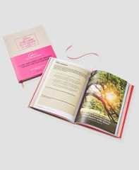 an open book sitting on top of a table next to a pink and white bag