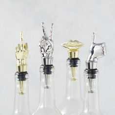 three glass bottles with gold and silver items in them on a white surface, one is empty