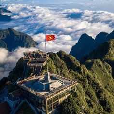 a flag on top of a mountain above the clouds