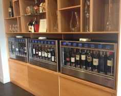 two wine coolers sitting next to each other in front of wooden shelves filled with bottles and glasses