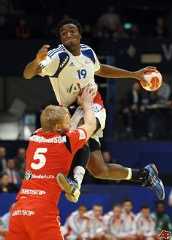 two men are playing basketball in front of an audience and one is jumping up to grab the ball