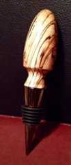 a wine bottle stopper made out of wood and black metal on a red surface