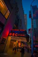 people are walking on the sidewalk in front of a building at night with neon lights