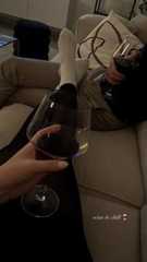 a person sitting on a couch with a glass of wine in front of their feet