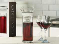 two wine glasses and a decanter sitting on a table next to each other