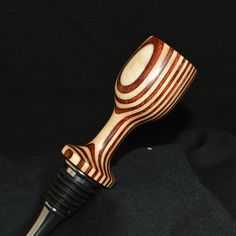 a close up of a wooden object on a black surface with a pen in it