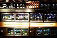 bottles of wine are lined up on shelves in a liquor store, with the lights turned on