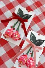 two valentine's day cards with candy hearts tied to them on a red and white checkered tablecloth