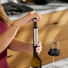 a woman holding a wine bottle in front of a glass