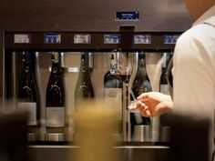 a person holding a wine glass in front of some bottles