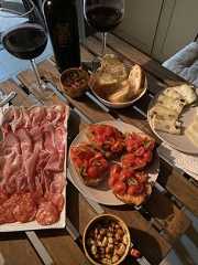 a table topped with plates of food next to wine glasses and bottles of red wine