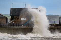 Waves crash against the harbour wall during Storm Ashley