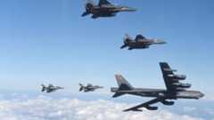 A US B-52 bomber in flight flanked by fighter jets