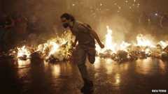 A demonstrator from the group called Black Bloc runs outside the Municipal Assembly during a protest supporting a teachers" strike in Rio de Janeiro