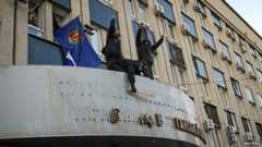Pro-Russian protesters remove the sign from the state security service building in Luhansk, eastern Ukraine, on 6 April 2014