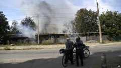 Locals watch the scene of shelling in Donetsk on 7 Sept
