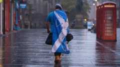 A lone "YES" campaign supporter walks down a street in Edinburgh
