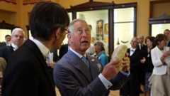 The Prince of Wales holds a marble head during a visit to Eton College near Windsor
