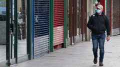 Man in mask walks past empty shops