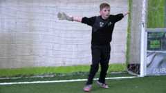 Boy standing in football goal with arms outstretched