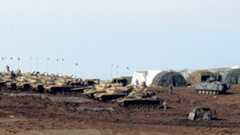 Turkish Army vehicles and tanks wait near the Syrian border in Suruc on February 23, 2015