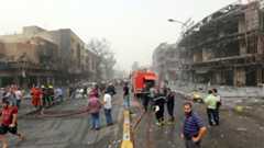 Iraqis, including firefighters, gather at the site of a suicide car bombing claimed by the Islamic State group on July 3, 2016 in Baghdad's central Karrada district