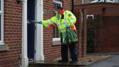 A Community safety patrol officer hands a coronavirus test to a resident in Bramley Green, Hampshire, during a surge testing programme after a case of the South African variant of Covid-19 was identified in the village