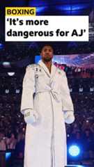 Boxer Anthony Joshua wearing a white robe and boxing gloves. He is standing in the ring in Wembley Stadium.