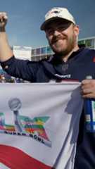 A patriots fan is holding a flag with his fist in the air.