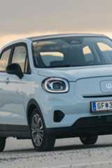 t03.jpg Ein hellblaues Elektroauto steht vor einer Bergkulisse.