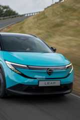 Ein türkisfarbener Nissan Leaf fährt auf einer kurvenreichen Straße. Ein türkisfarbener Nissan Leaf fährt auf einer kurvenreichen Straße.