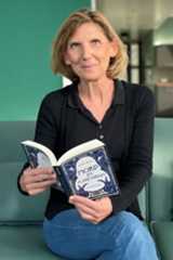 Beaty Maly sitzt auf einer Couch und blättert in ihrem neuen Buch