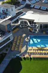 Großer Außenpool mit vielen gelben Liegestühlen, Wasserrutsche, Sonnenterrassen und einem runden Whirlpool auf dem Dach.