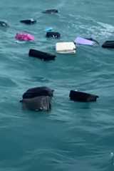 Mehrere Koffer treiben im offenen Meer auf den Wellen.