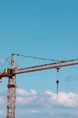 Ein Baukran ragt vor blauem Himmel und einigen Wolken empor.