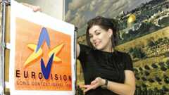 Eine Frau posiert neben einem Plakat des Eurovision Song Contest Israel 1999.
