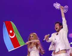 Ein Mann und eine Frau feiern mit der aserbaidschanischen Flagge und einer Trophäe.