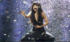 Eine Sängerin mit Mikrofon performt auf einer Bühne unter Konfettiregen.