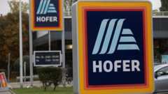 Ein Schild mit dem Hofer-Logo vor einer Hofer-Filiale.