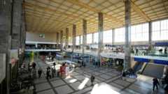 Die Haupthalle des Wiener Hauptbahnhofs mit Menschen und Geschäften.